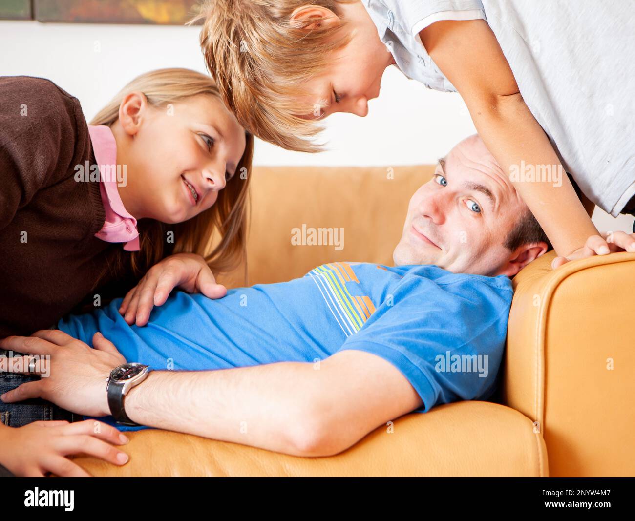 Family Life, Demanding Children. A wry smile from a father distracted by his cheeky persistent children from his nap. From a series of related images. Stock Photo