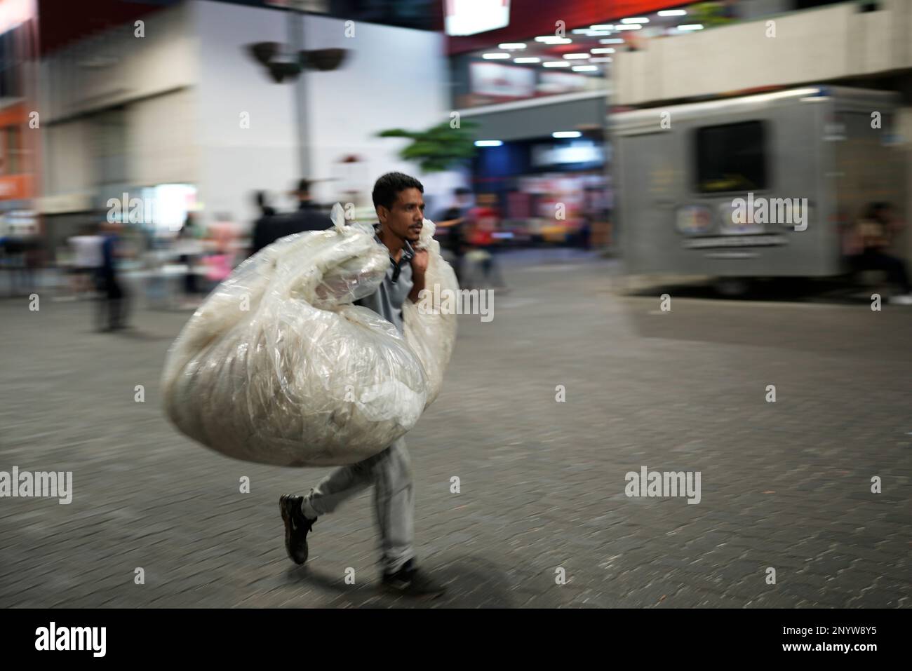 A man carries bags of items thrown away by others that he hopes to sell as recyclable material