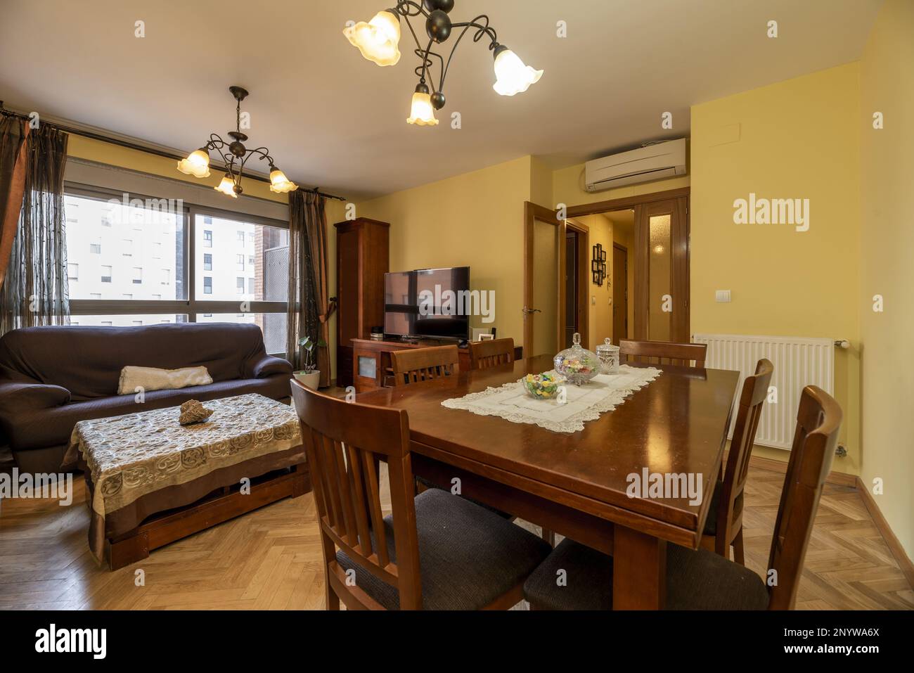 Living-dining room of a house with dark wood furniture, walls painted pale yellow and French oak parquet floors Stock Photo