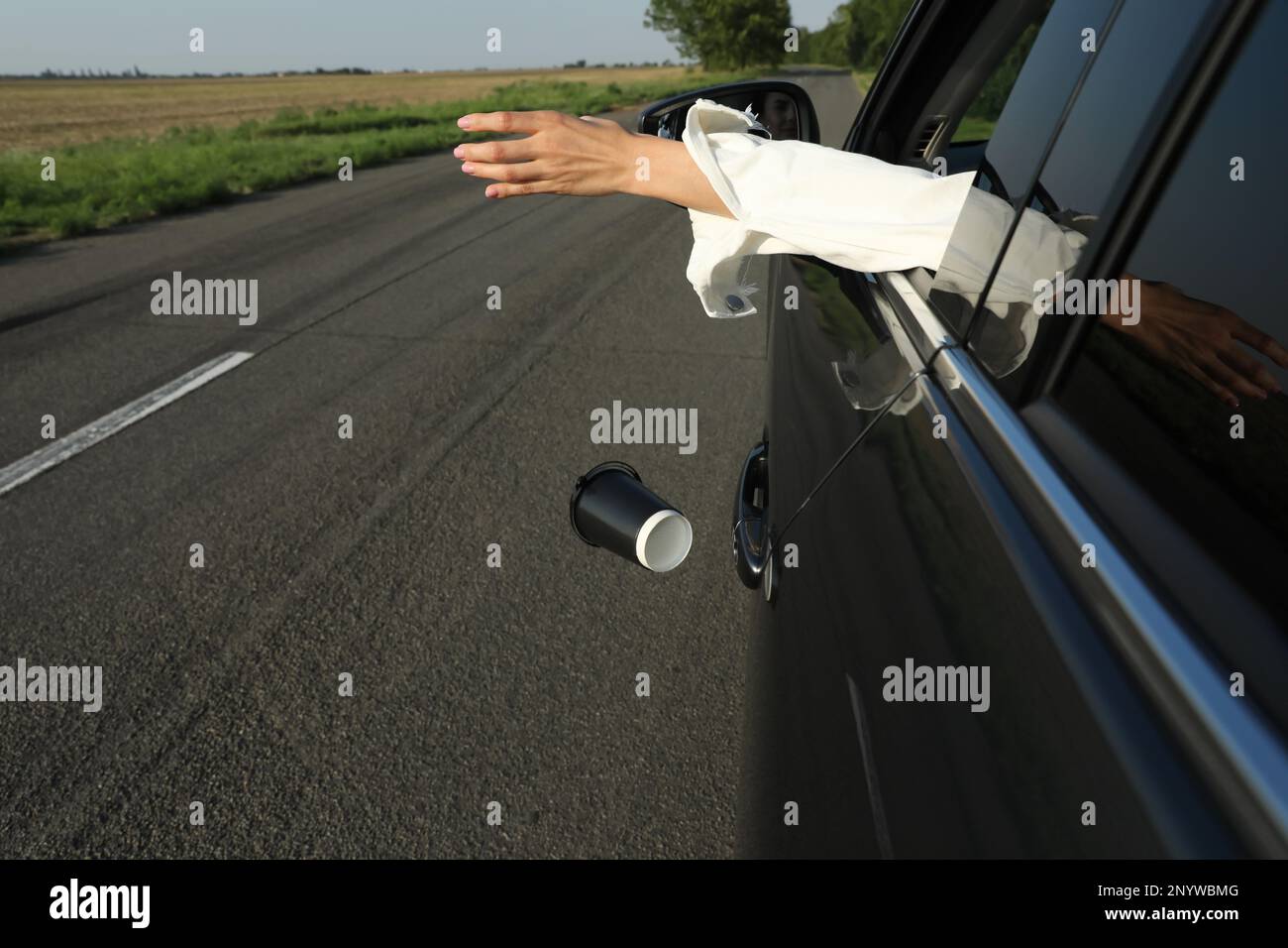 Driver throwing away paper cup from car window. Garbage on road Stock