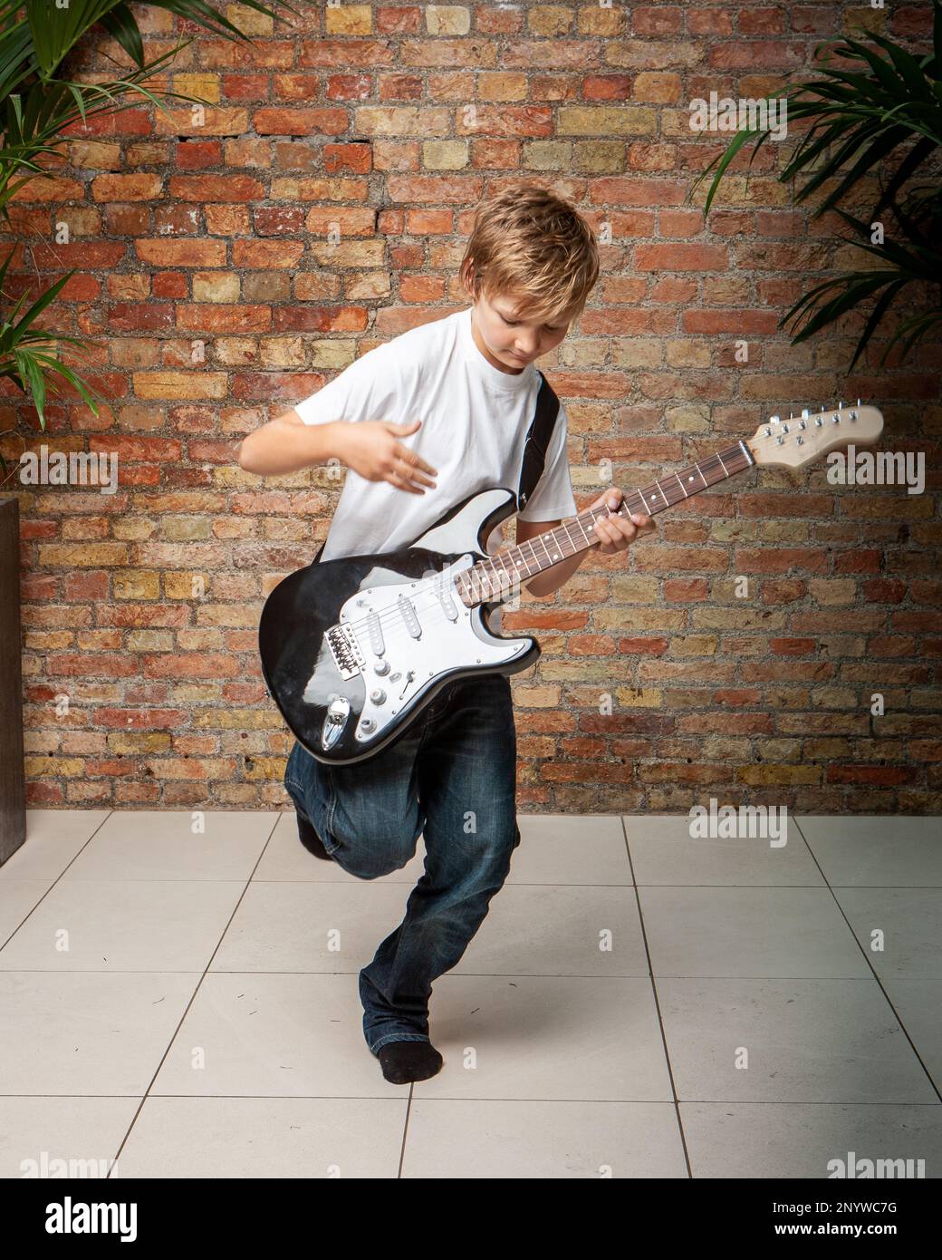 Family Life, Rock Guitarist. A young boy in an energetic mood enjoying playing his electric guitar. From a series of related images. Stock Photo