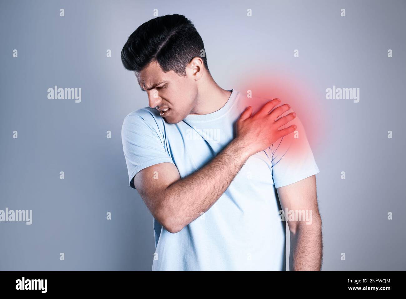 Man suffering from shoulder pain on grey background Stock Photo