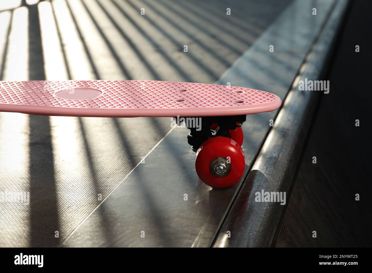 Pink Ramp Model Modern pink skateboard with red wheels on top of ramp outdoors, closeup ...