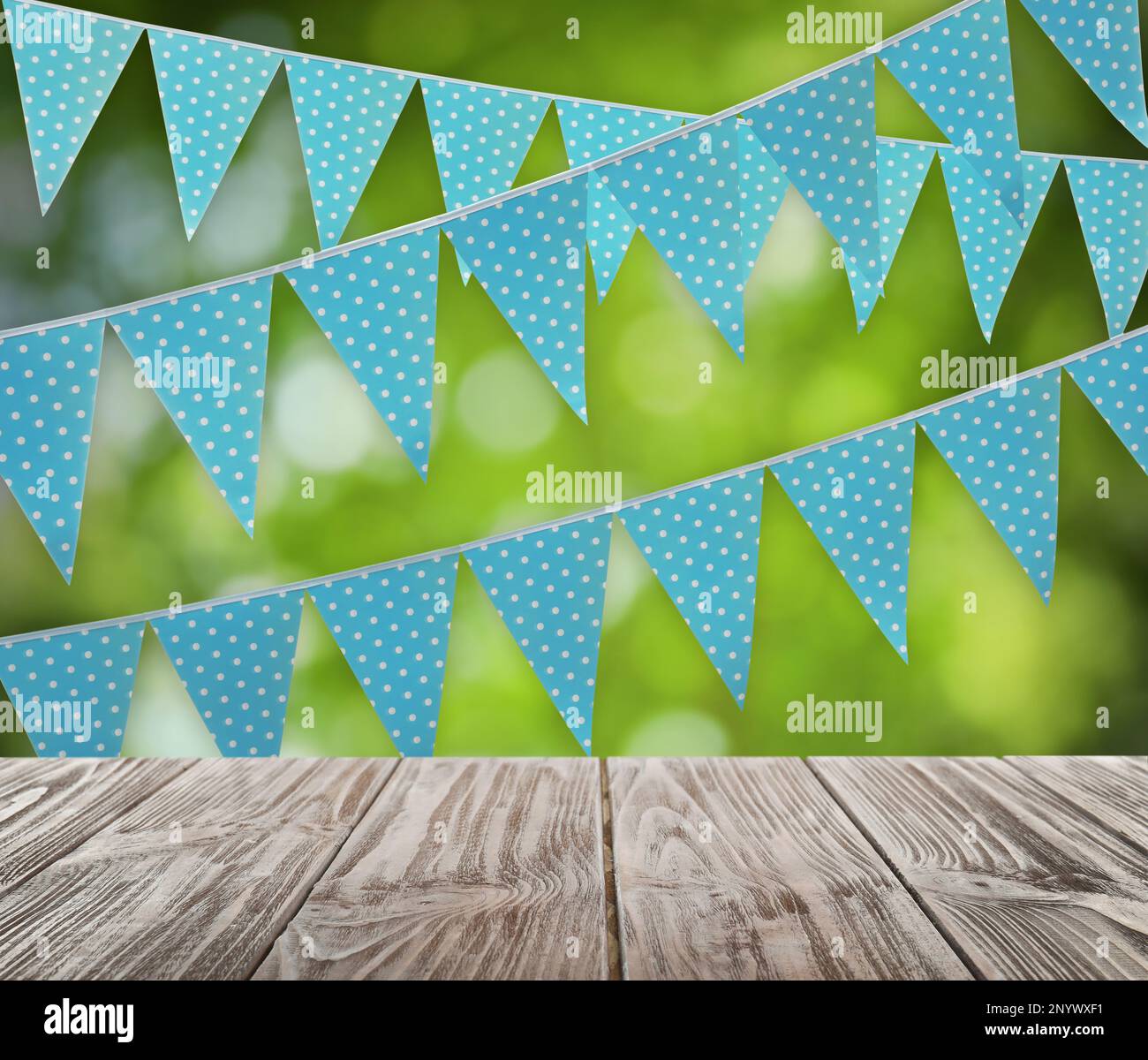 Empty wooden table and decorative bunting flags outdoors Stock Photo