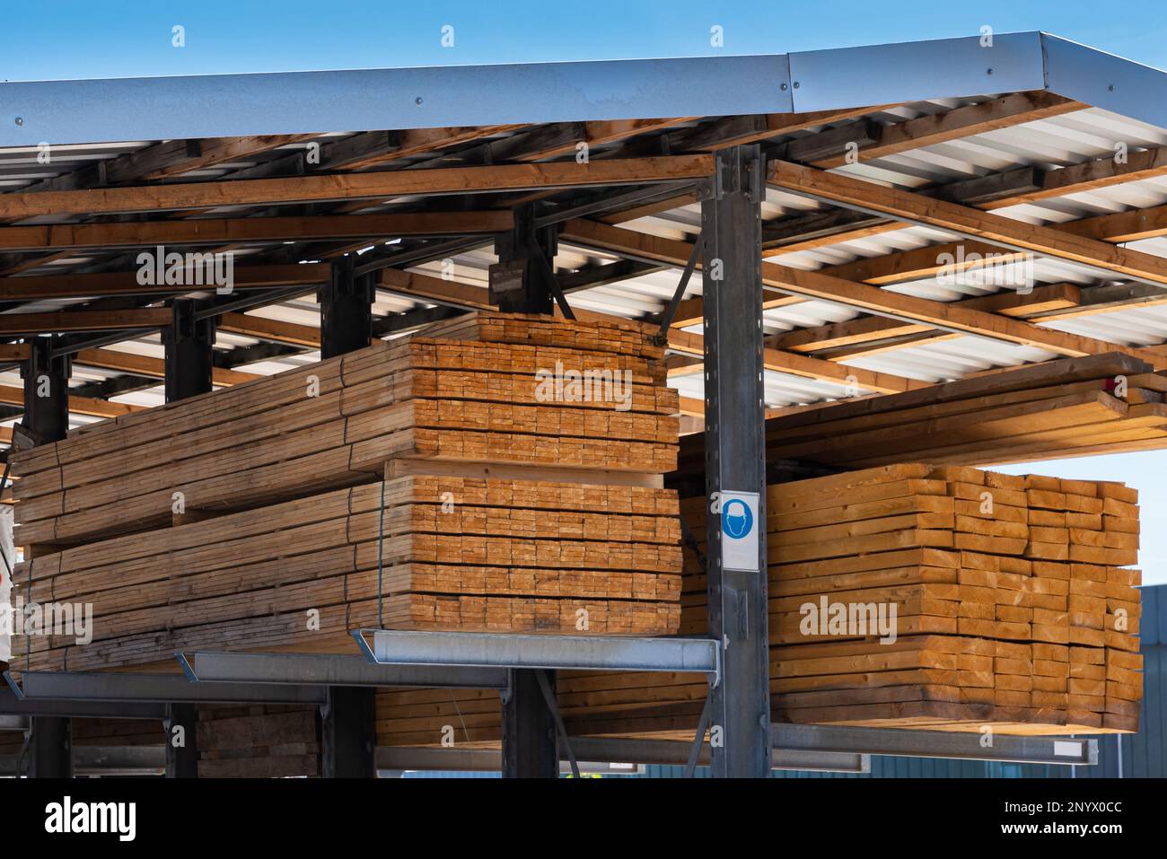 An edging board in stacks on metal scaffolds under the roof Stock Photo