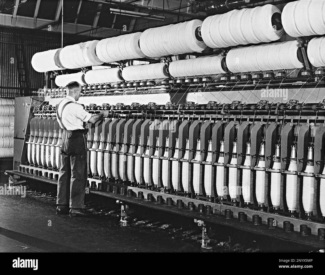 Man operating spinning machine for making carpet at Brintons Carpets, 1960s. Man operating spinning machine. Stock Photo