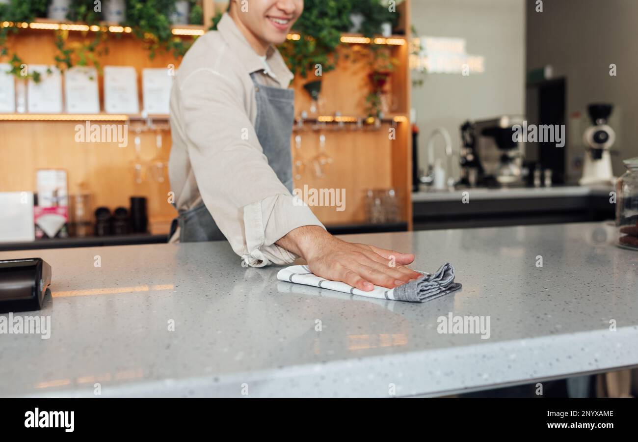 Unrecognizable bartender wiping bar counter. Barista cleaning a counter ...