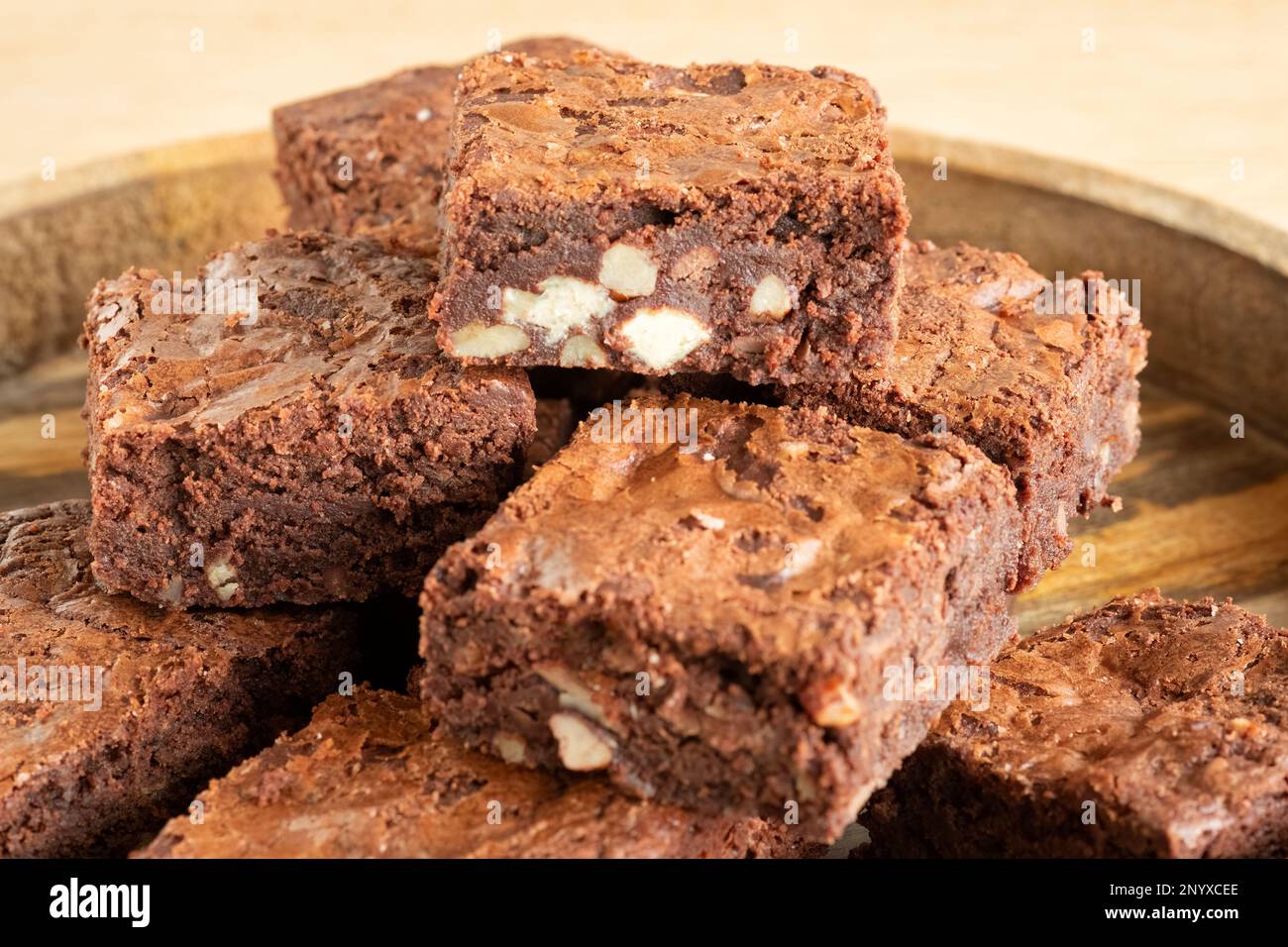 A batch of freshly home baked triple chocolate brownies arranged on a wooden platter. The brownies are still warm and gooey. an indulgent treat Stock Photo