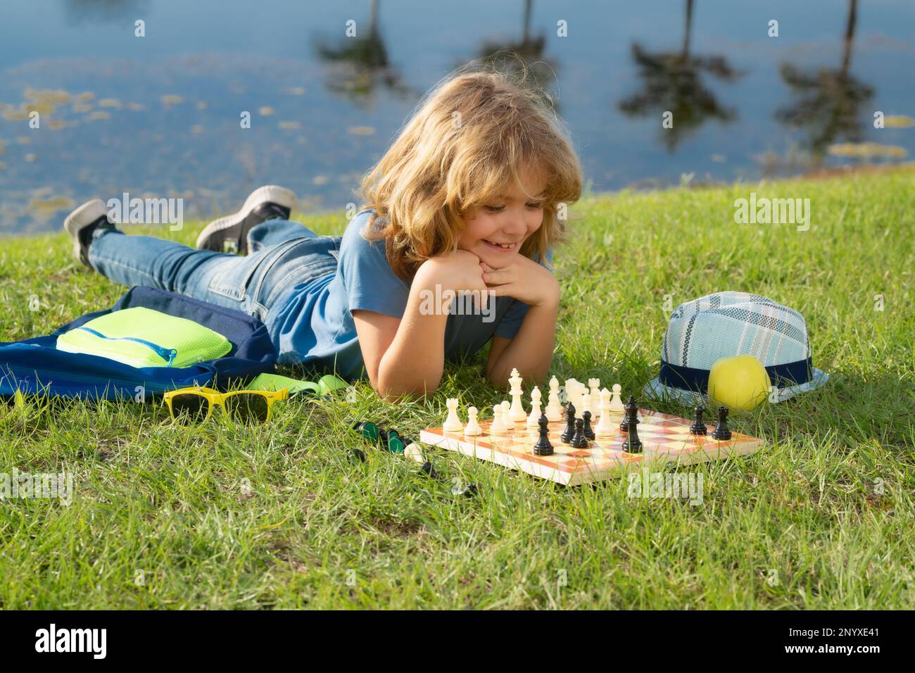 Little kid play chess in park. Child boy playing board game outdoor. Thinking child brainstorming and idea in chess game Stock Photo