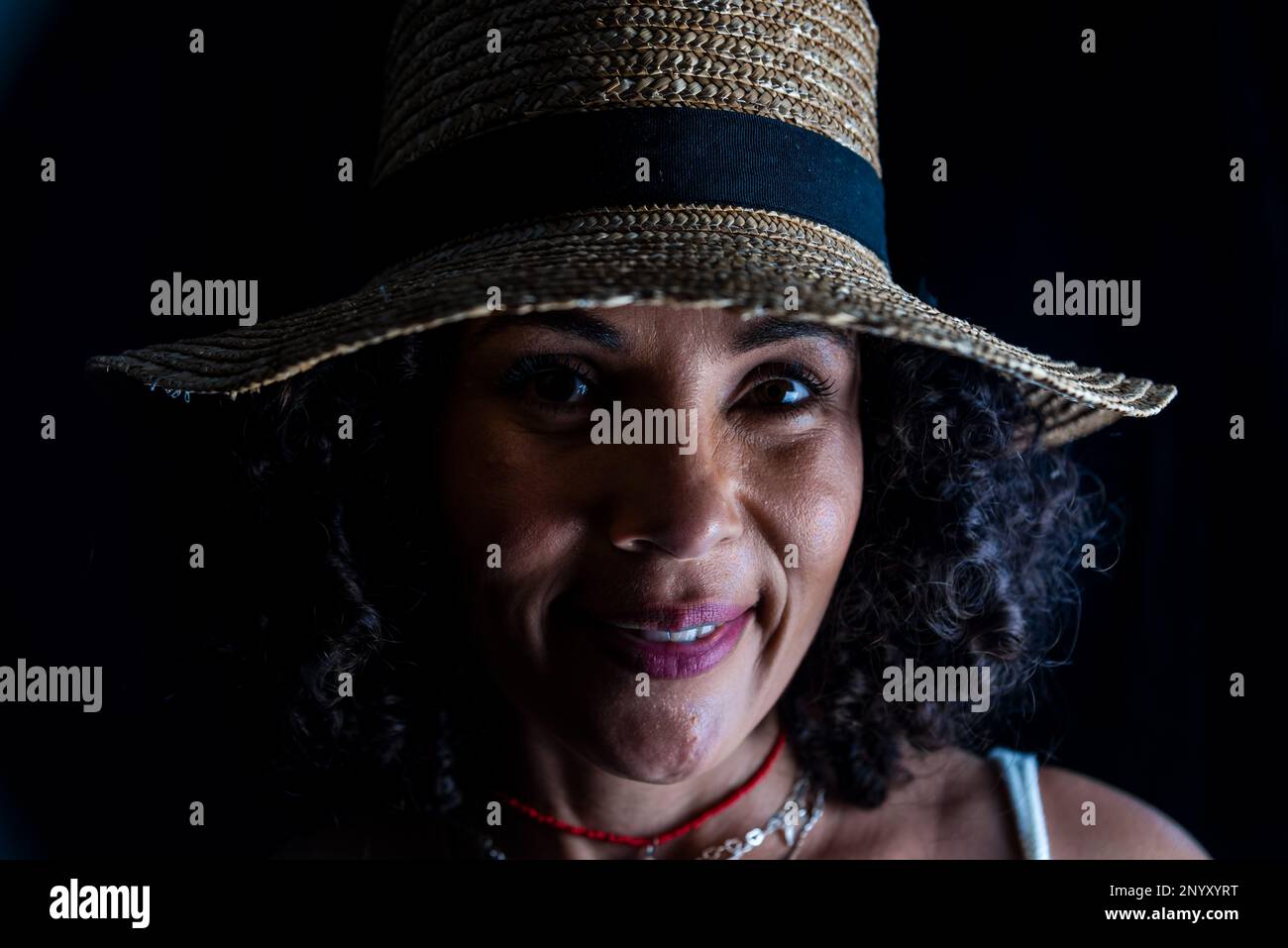 Close-up portrait of a pretty woman wearing a brown hat against a black ...