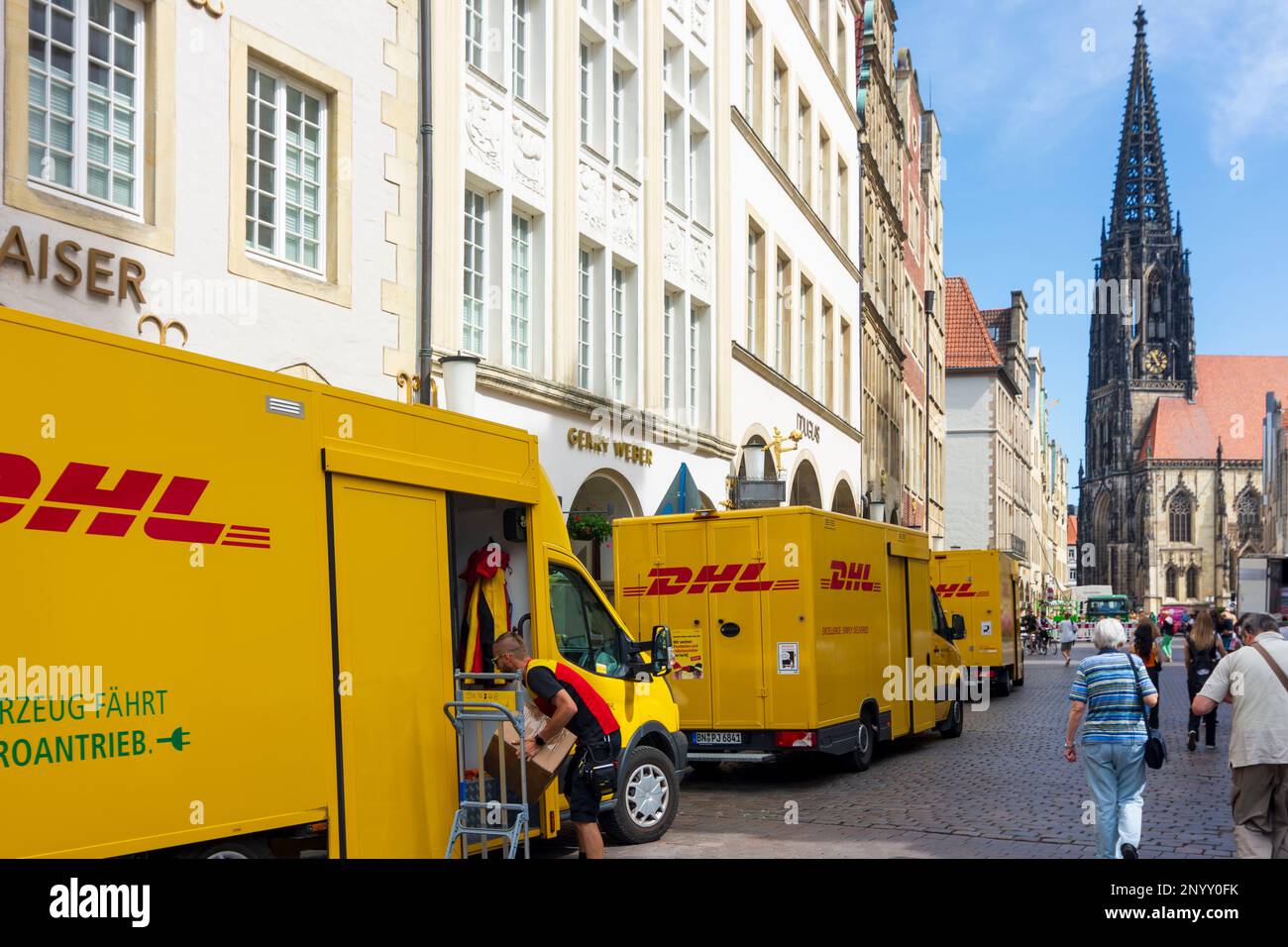 Münster: 3 delivery vans of DHL in a line, issue of delivery logistics in inner cities, square Prinzipalmarkt, church St. Lamberti in Münsterland, Nor Stock Photo