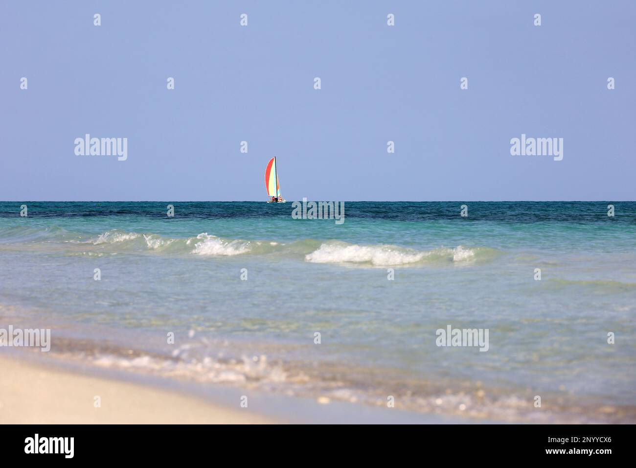 View to sailboat in blue ocean from sand beach and water surface. Background for sea holidays Stock Photo