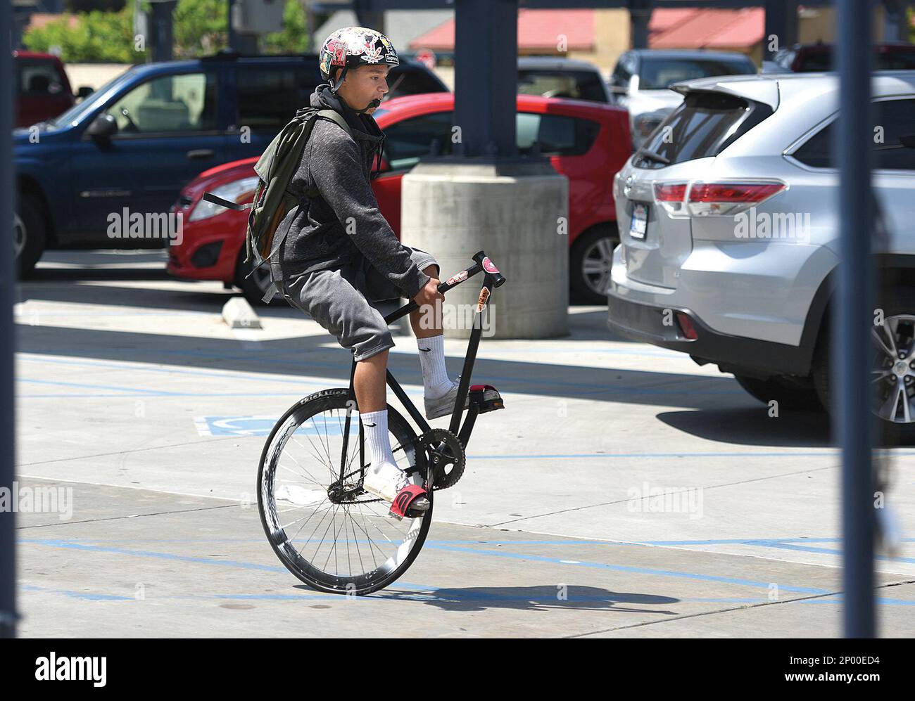 A unicyclist cruises among parked cars Saturday in the parking lot