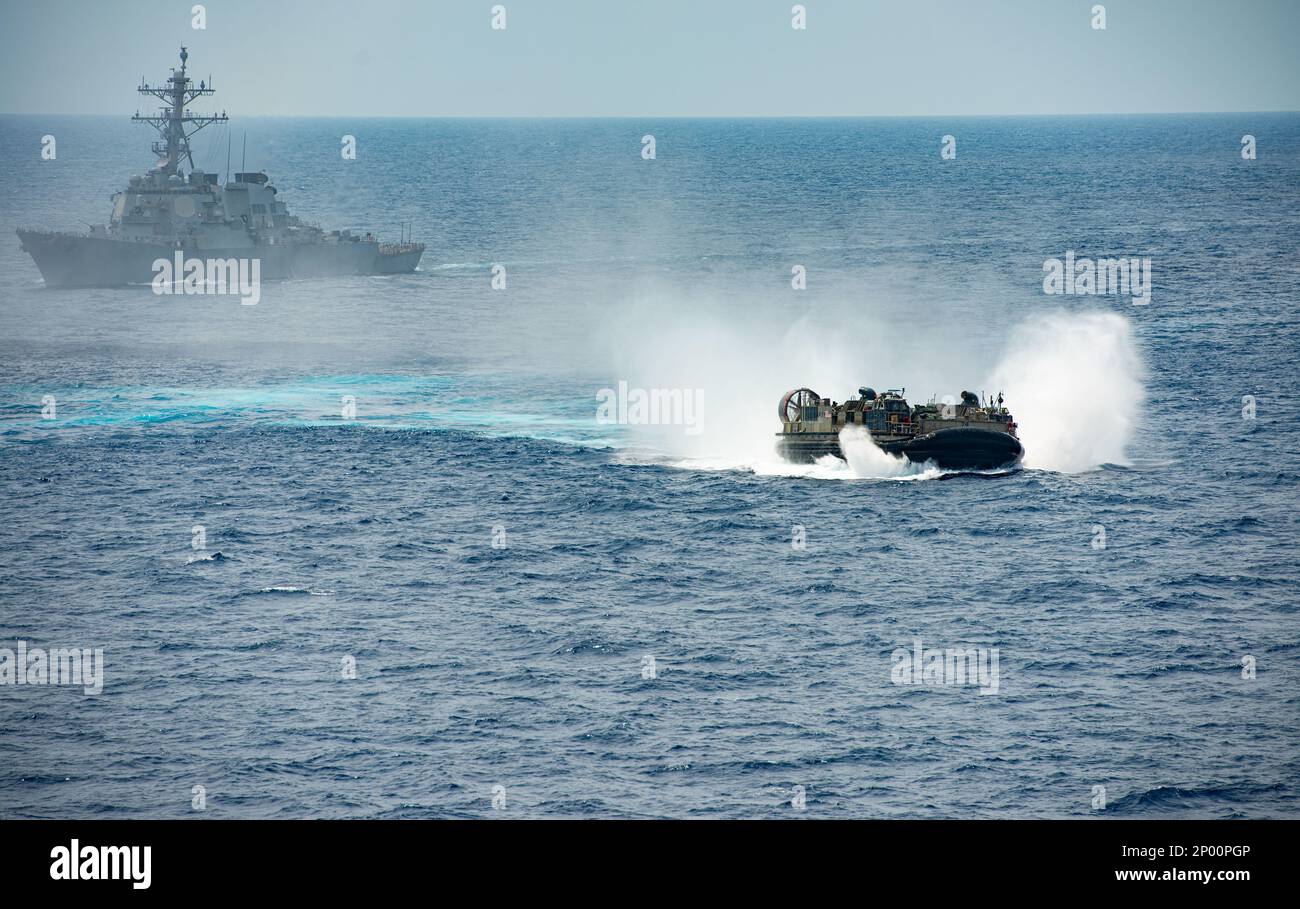 230215-N-WM182-2106 SOUTH CHINA SEA (Feb. 15, 2023) A landing craft, air cushions (LCAC) from Assault Craft Unit (ACU) 5 maneuvers near the Arleigh Burke-class guided-missile destroyer USS Decatur (DDG 73). Nimitz Carrier Strike Group (NIMCSG) and Makin Island Amphibious Ready Group (MKI ARG), with embarked 13th Marine Expeditionary Unit (MEU), are conducting combined expeditionary strike force (ESF) operations, demonstrating unique high-end war fighting capability, maritime superiority, power projection and readiness. Operations include integrated training designed to advance interoperability Stock Photo