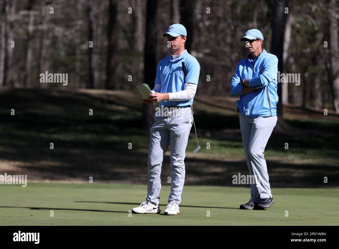KANNAPOLIS, NC - APRIL 09: North Carolina's Austin Hitt (left) putts on the  12th hole with help from head coach Andrew Sapp (right). The third round of the  Irish Creek Intercollegiate Men's