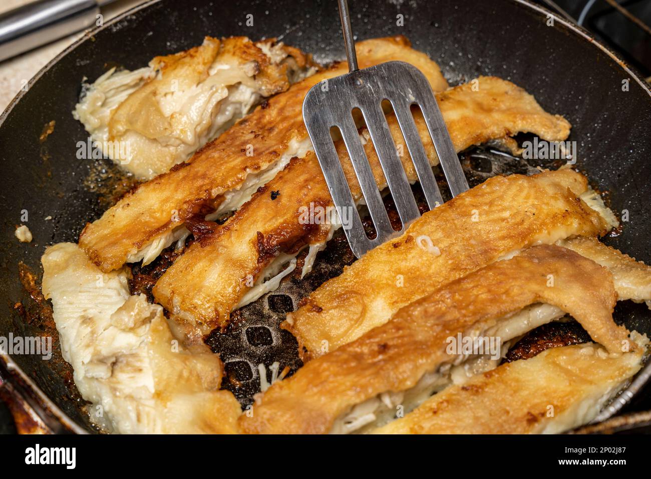 the cook checks the readiness of the fish with a fork Stock Photo - Alamy