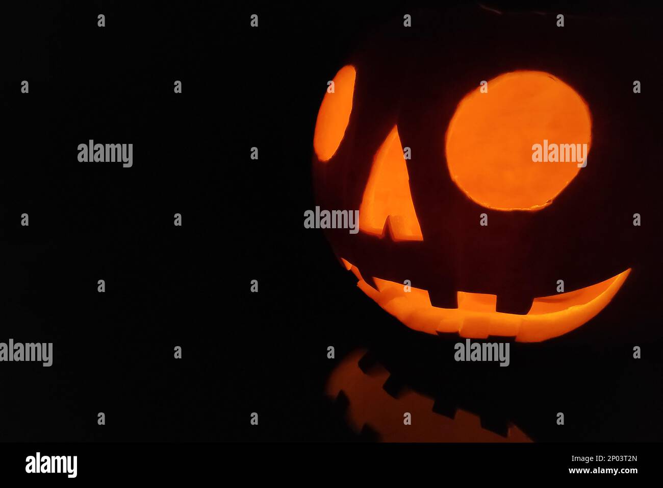 Close-up on a Jack O' Lantern reflecting on a black surface. Stock Photo