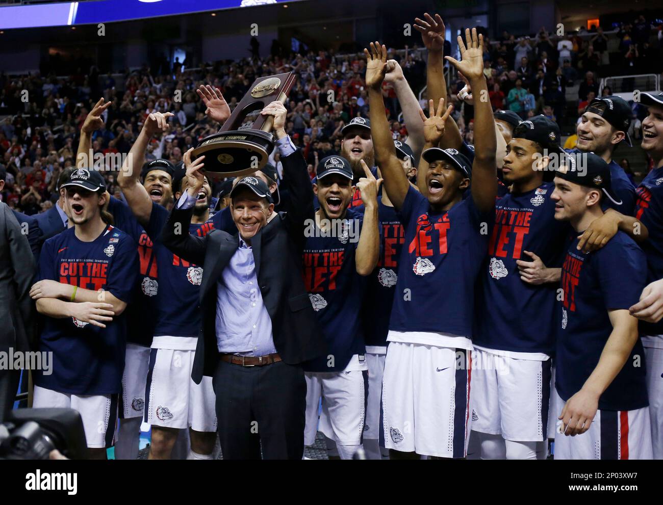 Gonzaga head coach Mark Few, center, holds a trophy with his team after beating Xavier during an