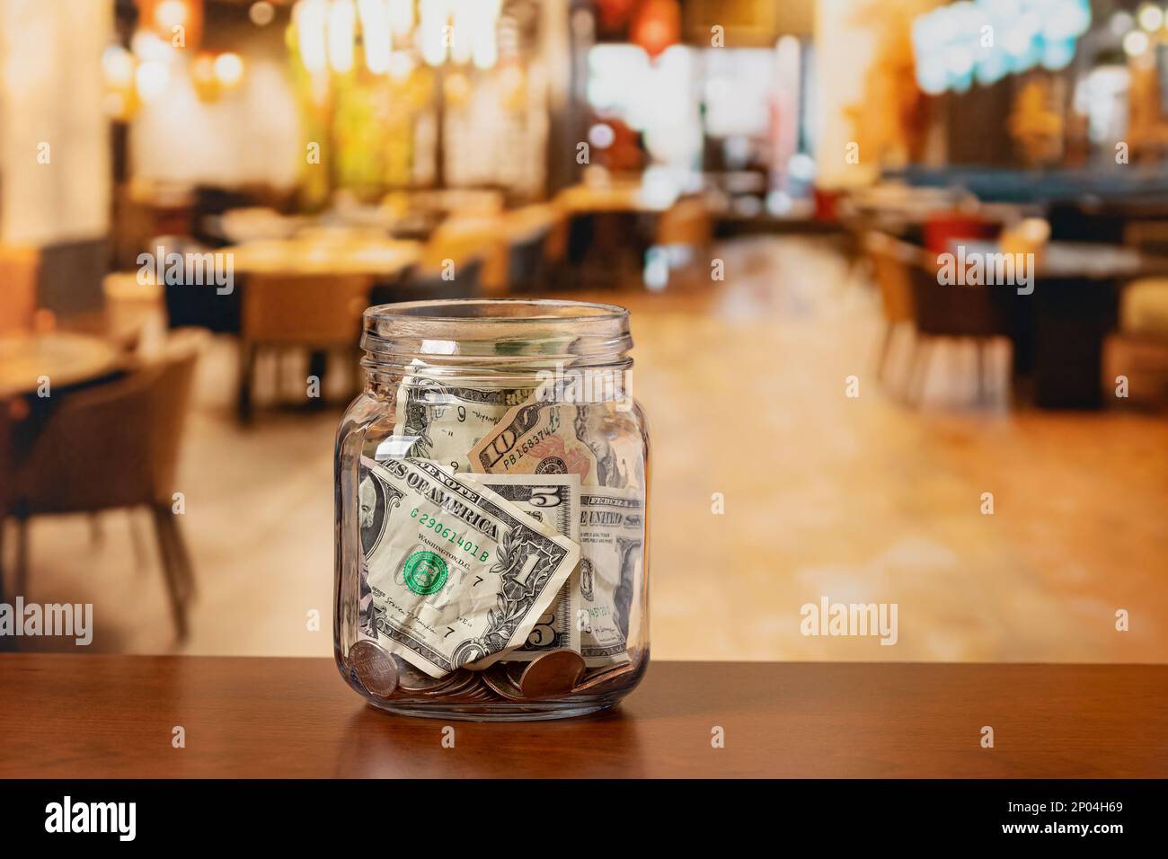 Tip jar in restaurant dining room. Service industry tipping, minimum wage and gratuity concept. Stock Photo