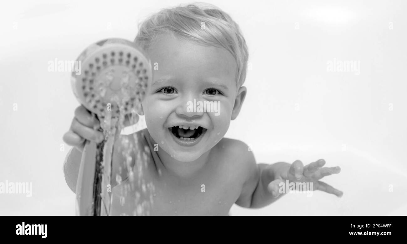 Childs hygiene. Funny baby playing with water and foam in a big kitchen