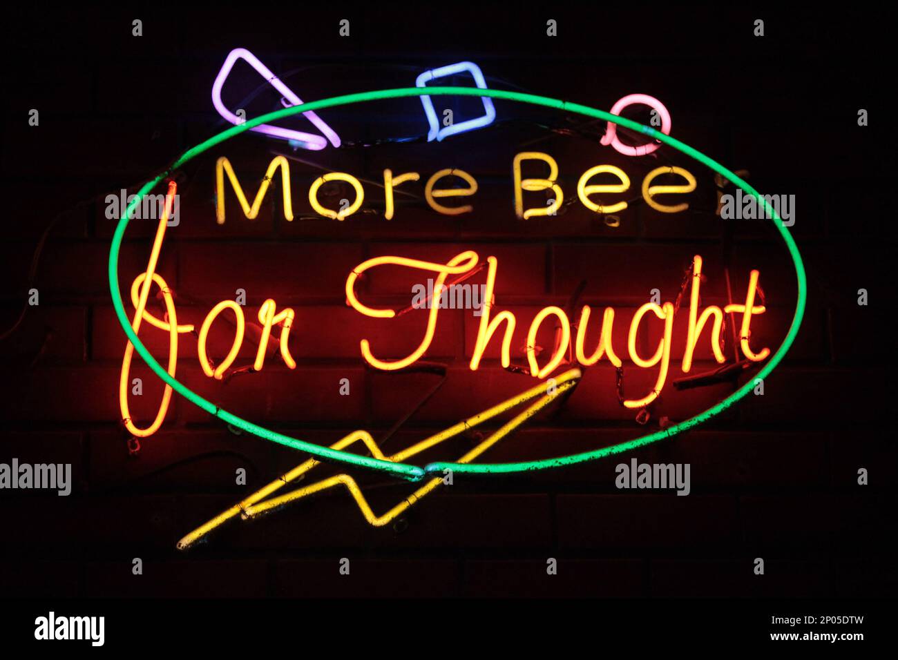 A neon light shaped into an circle with written inside the phrase 'More Beer for Thought'. Stock Photo