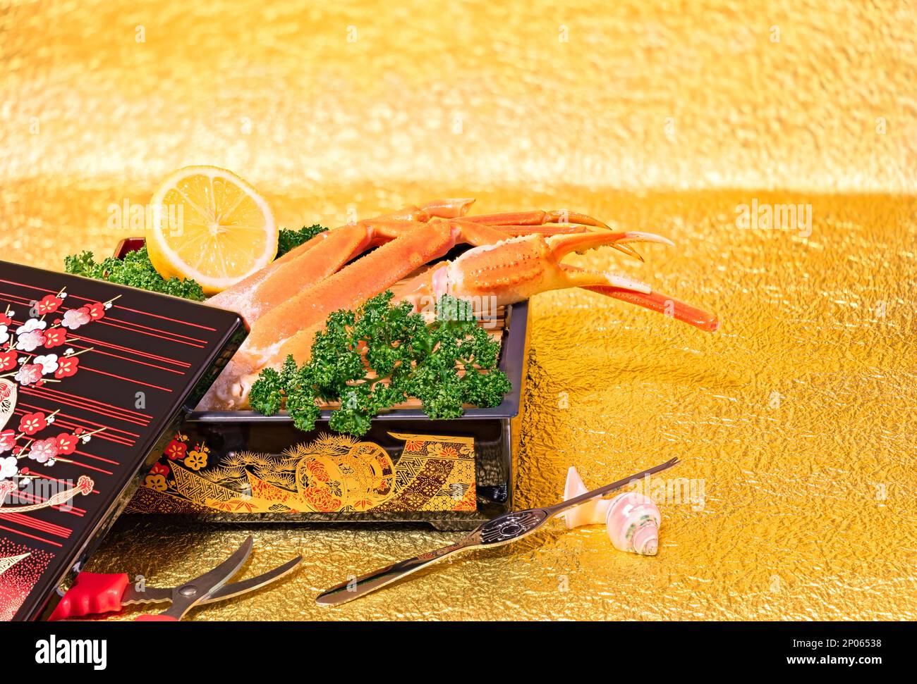 Japanese fresh raw king crab legs arranged in a luxurious box adorned with golden traditional motifs, and accompanied by seafood cutlery such as plier Stock Photo