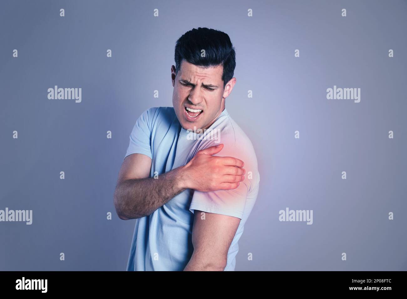 Man suffering from shoulder pain on grey background Stock Photo
