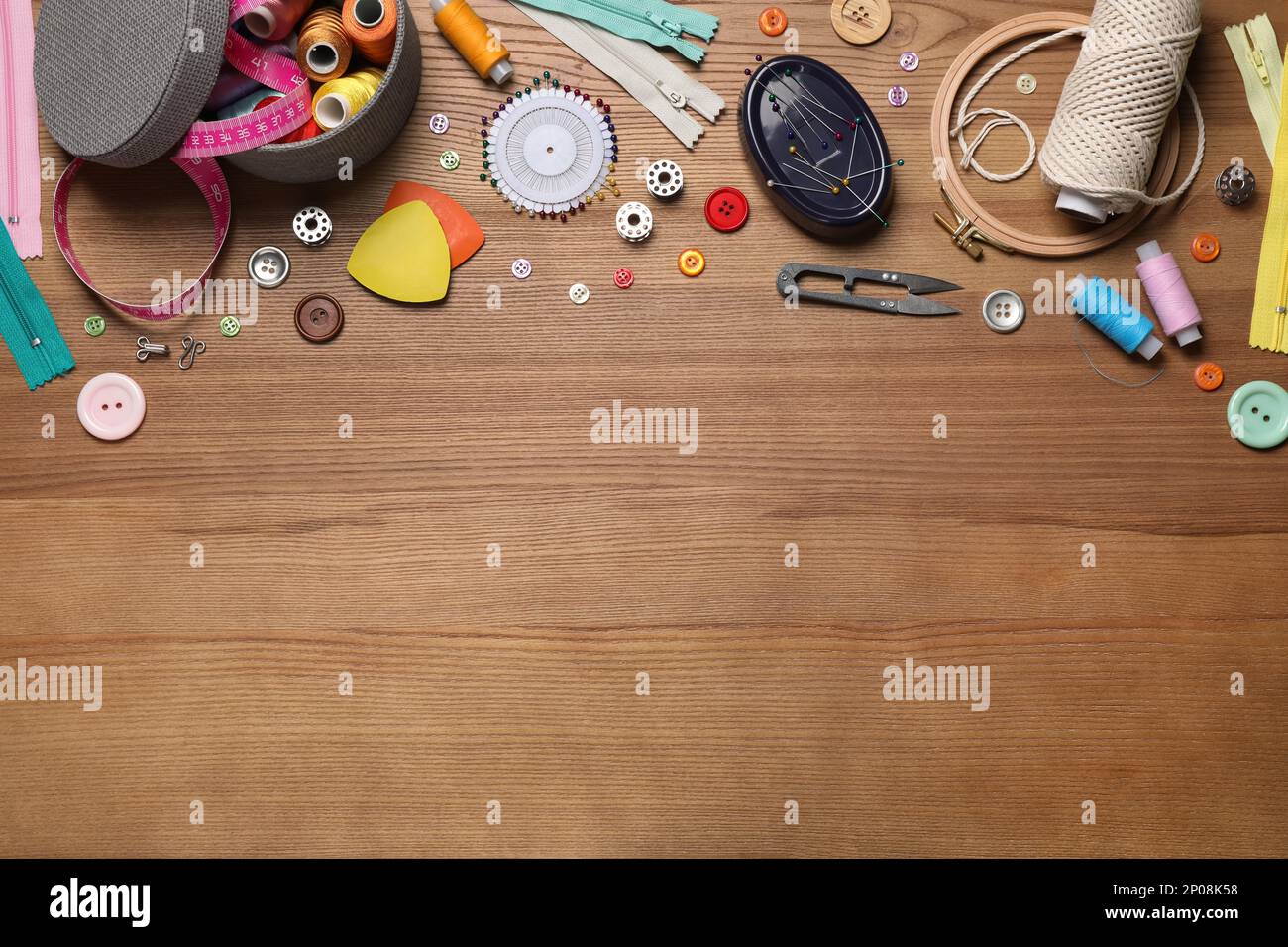 Flat lay composition with different sewing accessories on wooden background. Space for text Stock Photo