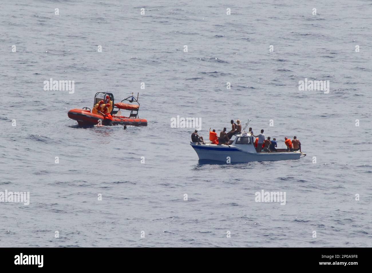 3 desperate migrants enter the water as Aurora’s rapid response RIB attempts an organised rescue of 23 migrants adrift in the Med without power. Stock Photo