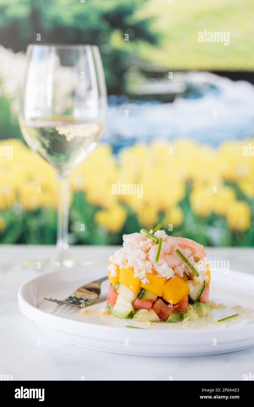 A crab and shrimp stacked salad served with a glass of white wine in ...