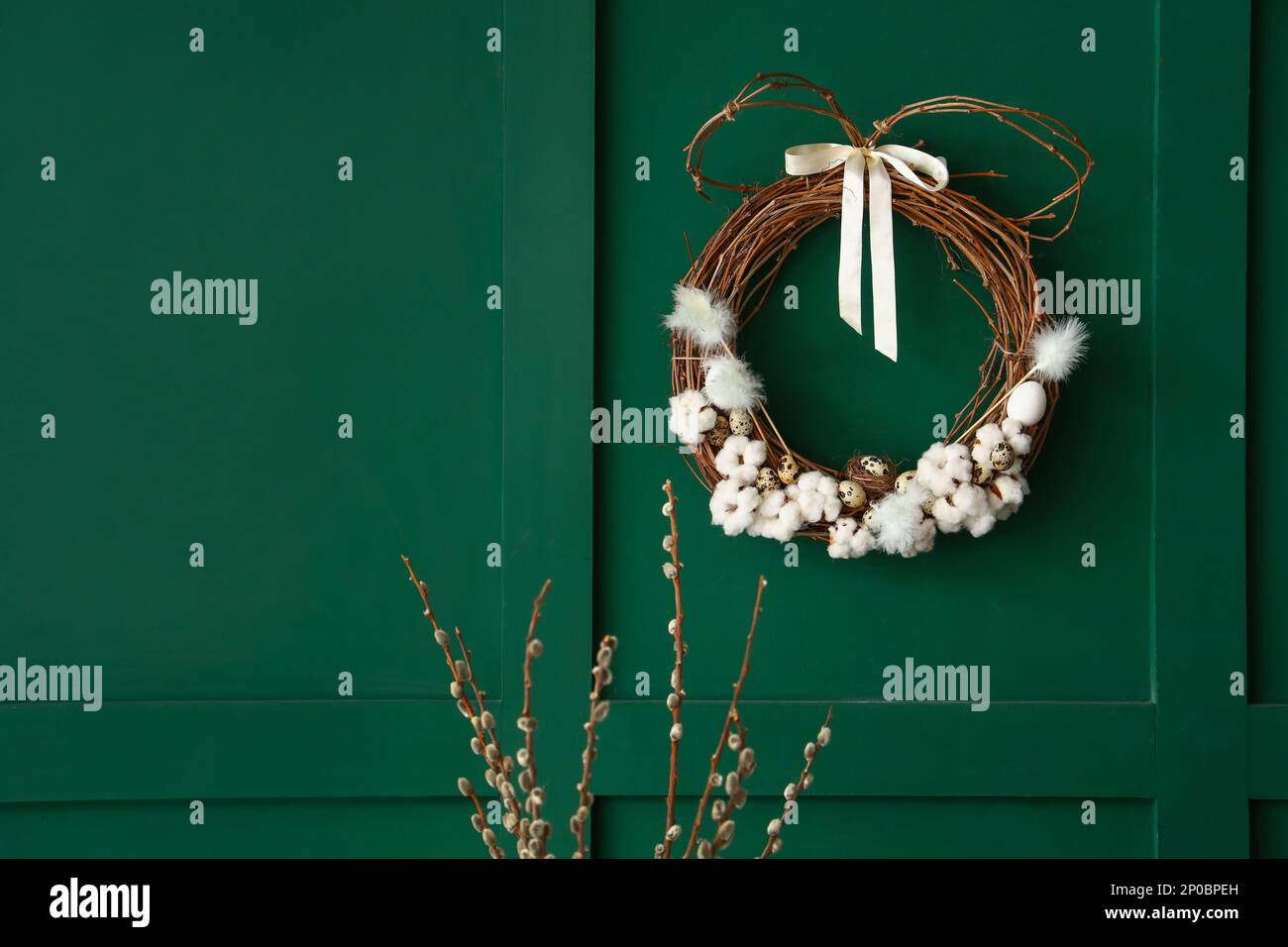 Willow branches and Easter wreath on green wall Stock Photo