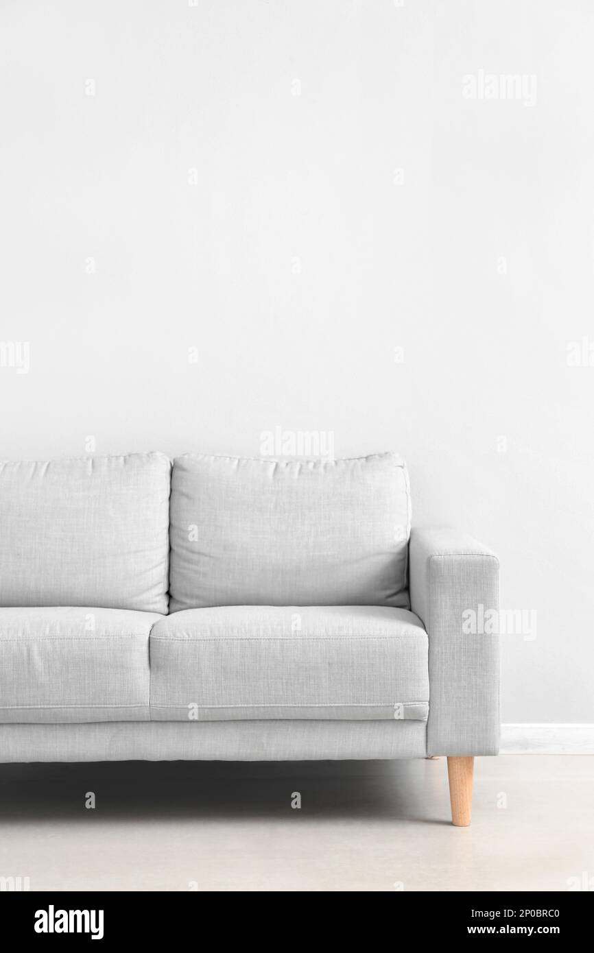 Stylish grey sofa near white wall Stock Photo - Alamy