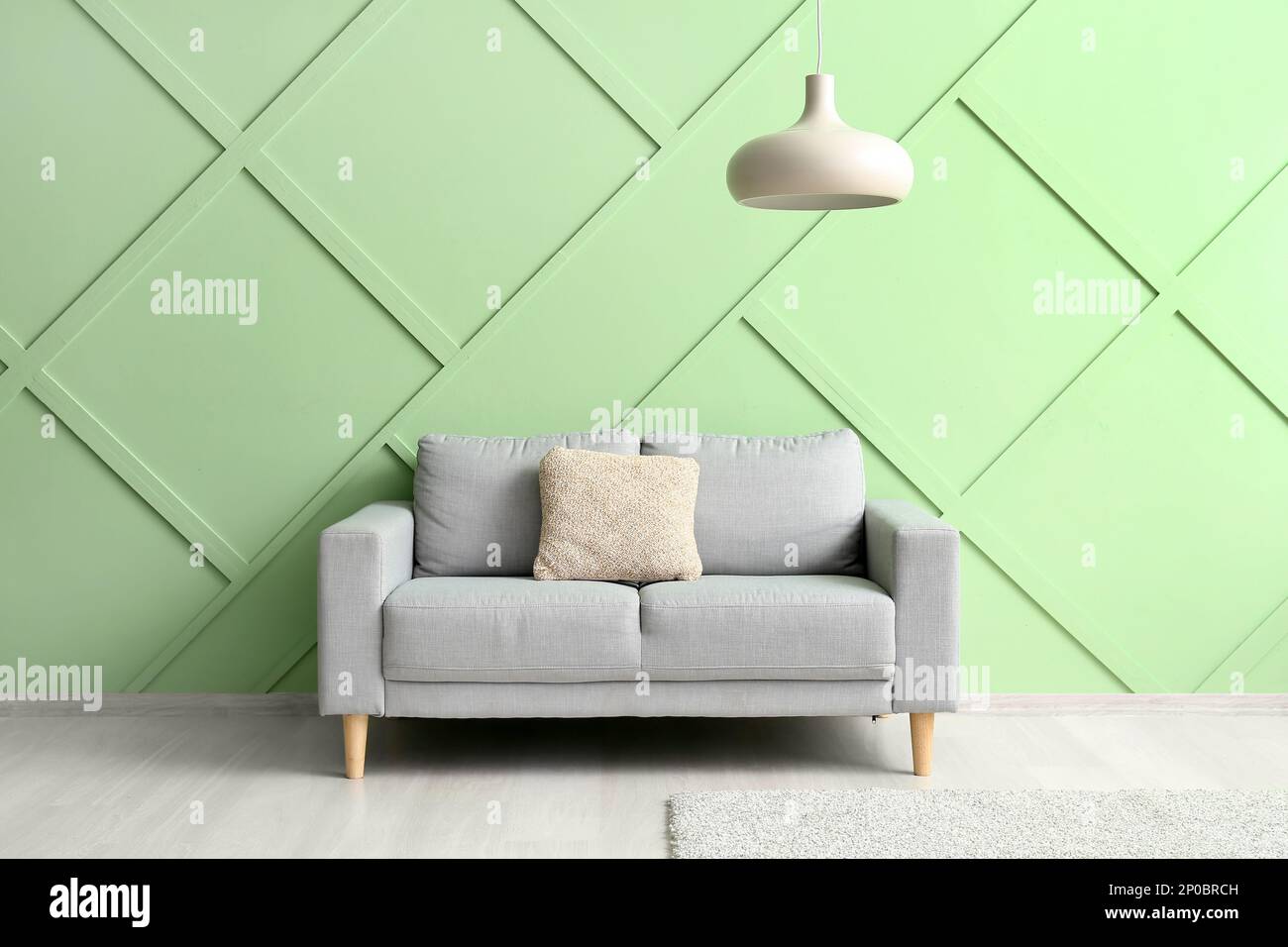 Stylish grey sofa near green wall Stock Photo - Alamy
