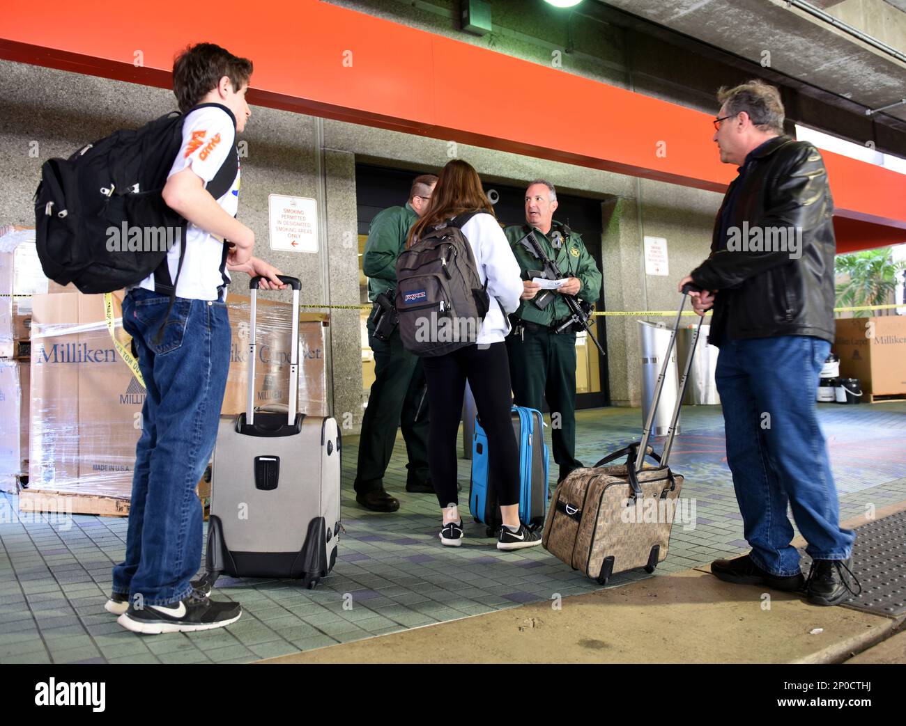 A Broward Sheriff Office Deputy talks with airport passengers outside