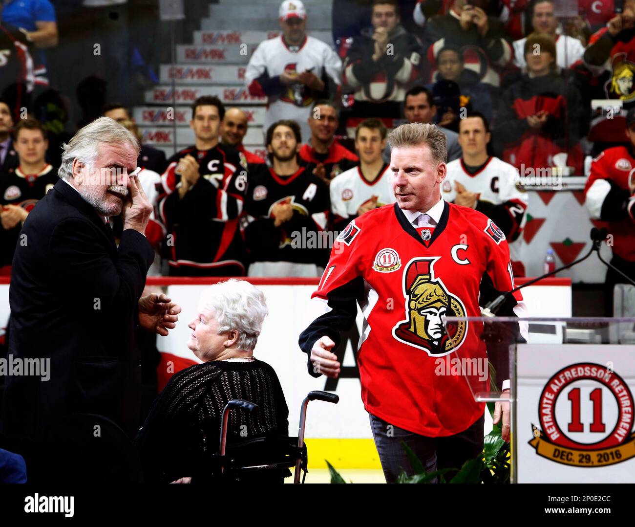 Former Ottawa Senators player Daniel Alfredsson makes his way to the ice as his father Hasse Alfredsson left wipes tears and his mother Margareta looks on during a ceremony retiring Alfredsson s Senat...