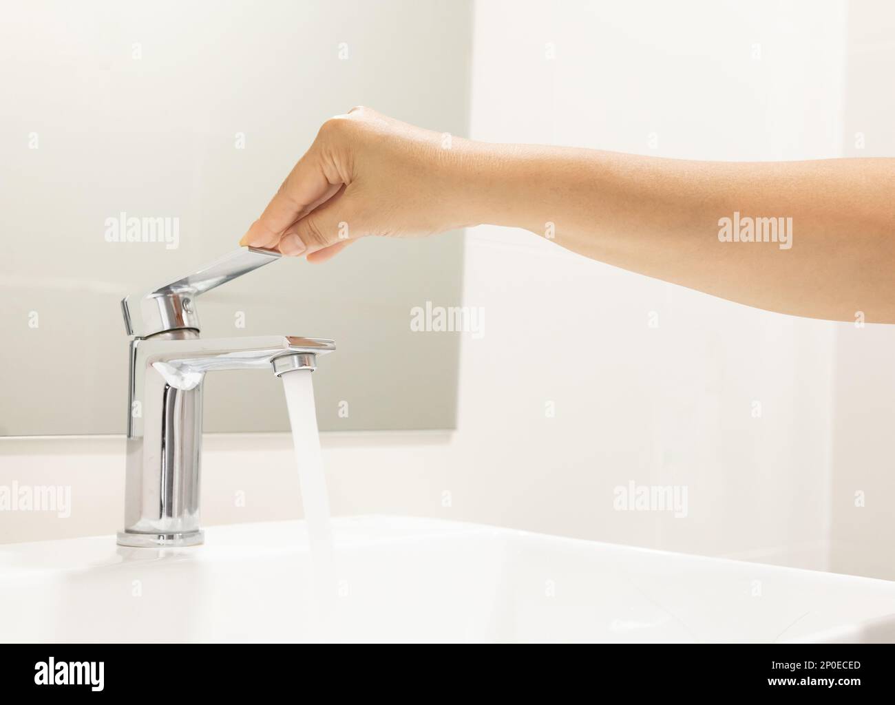 close up Woman open pull chrome faucet washbasin to washing hand soap for corona virus at water tap. push off water running drop off. Bathroom Stock Photo