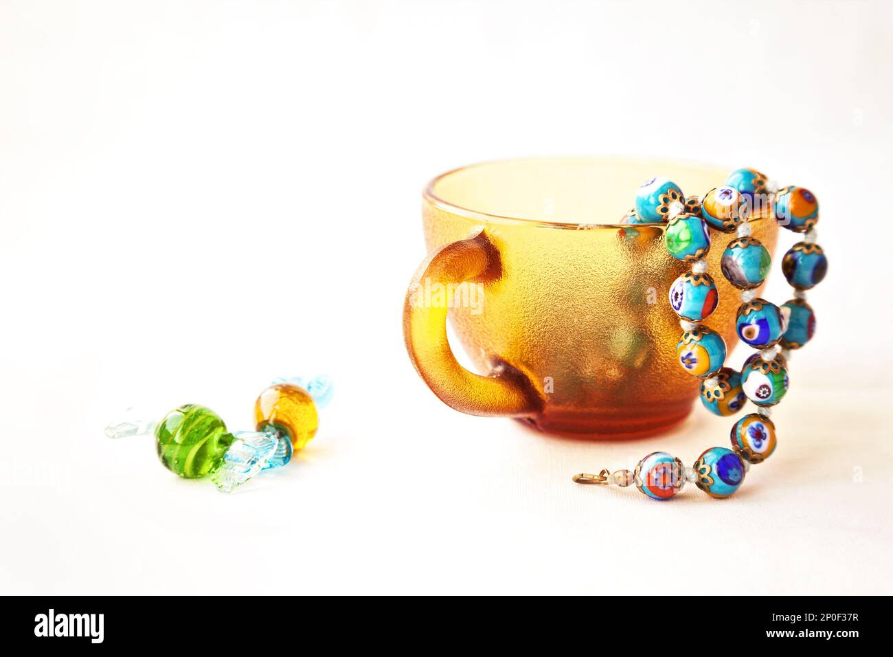 Original colorful Murano glass beads and candies. Venetian traditional millefiori necklace in a coffee cup. String of blue  beads Stock Photo