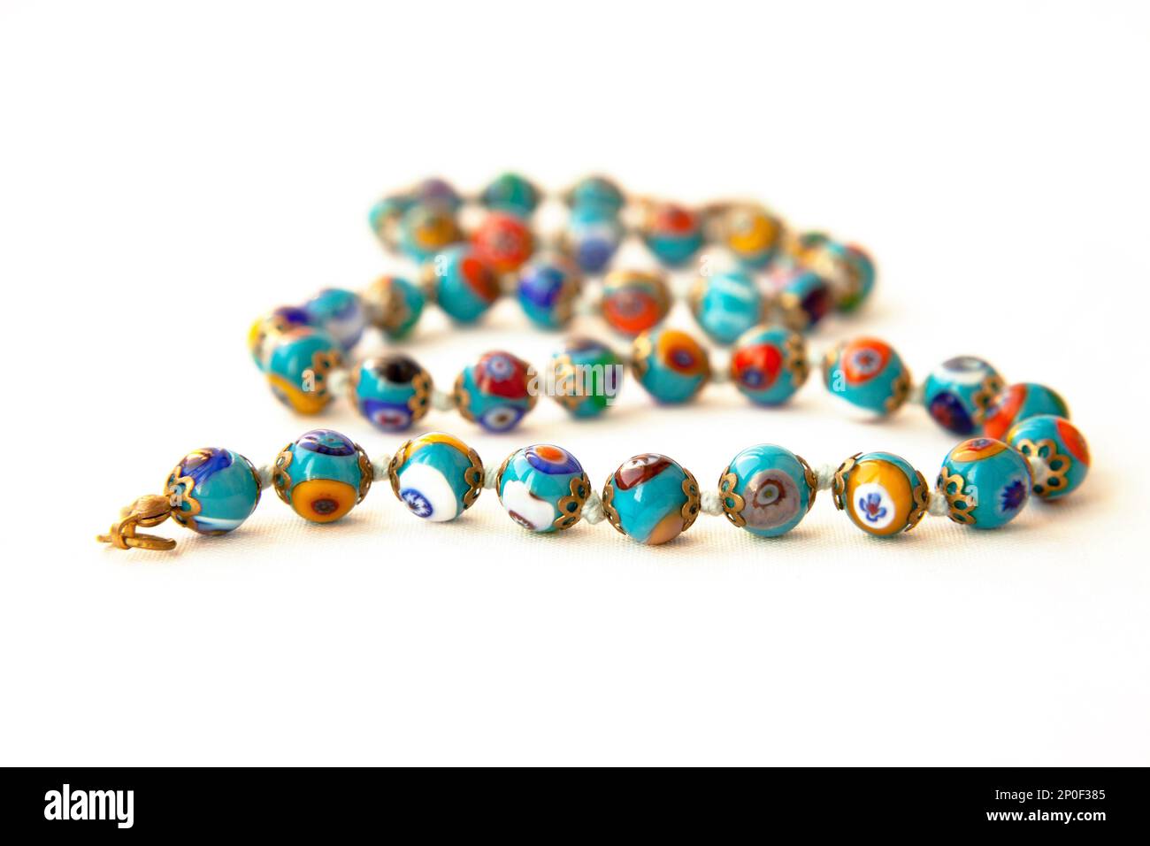 Original Murano glass beads with floral pattern necklace isolated. Venetian traditional colorful millefiori glass jewelry. String of blue  beads, focu Stock Photo