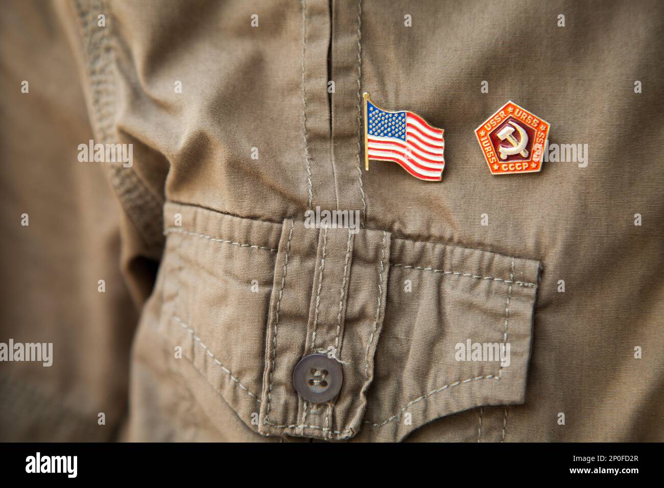 USSR & USA flag, historic national emblem on a khaki shirt person chest: Stars and stripes, hammer and sickle close-up. Partnership or confrontation Stock Photo