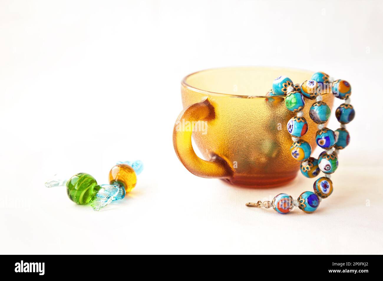 Original colorful Murano glass beads and candies. Venetian traditional millefiori necklace in a coffee cup. String of blue  beads Stock Photo