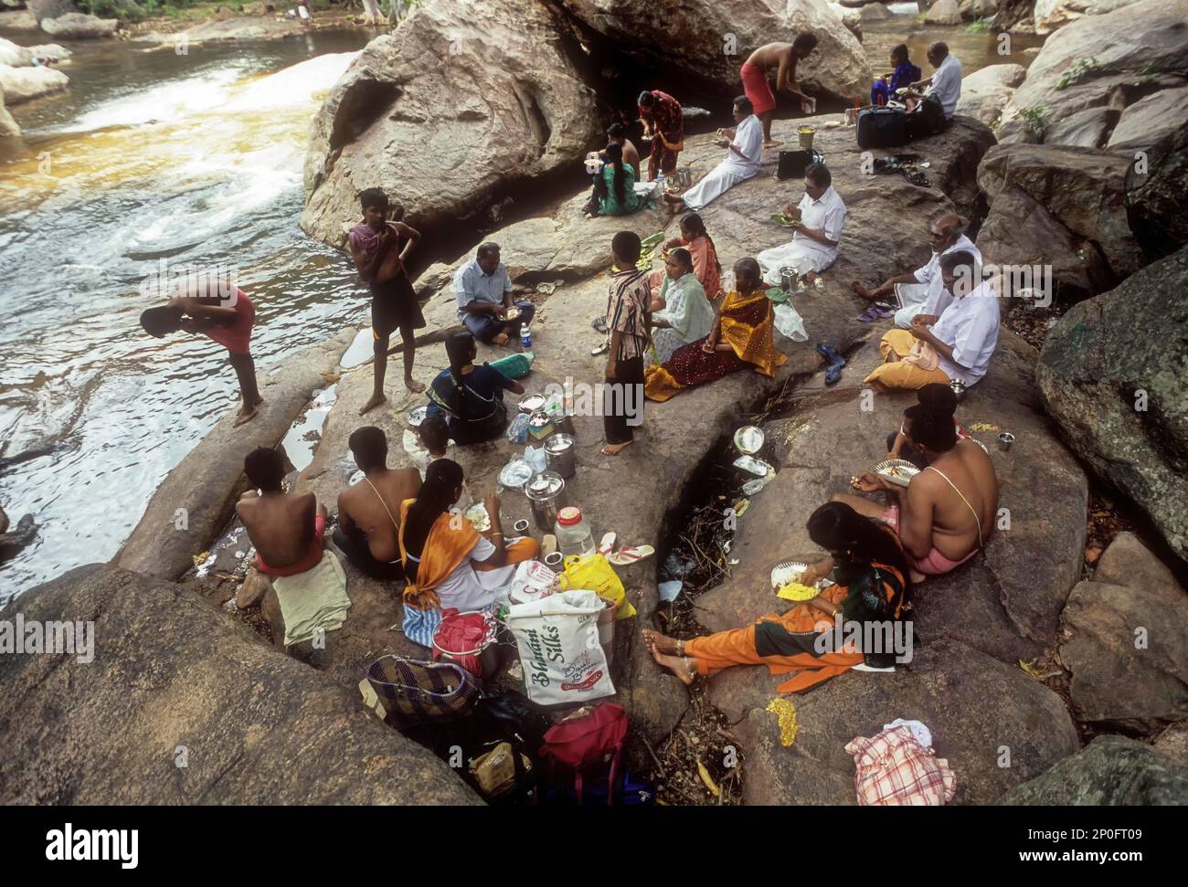 Tourists having a picnic, sitting on the rocks and eating at