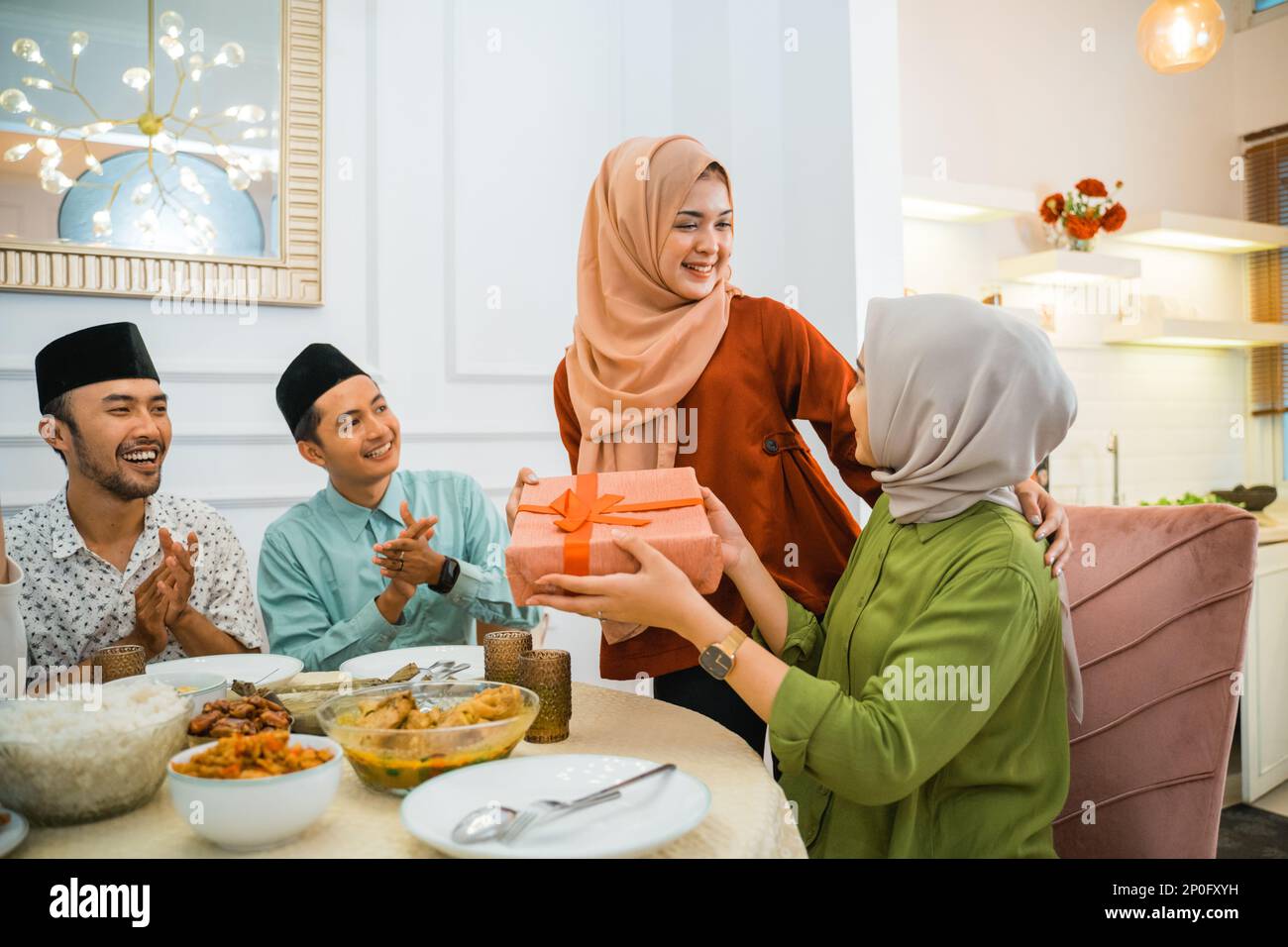 woman in hijab giving a gift to a female friend Stock Photo