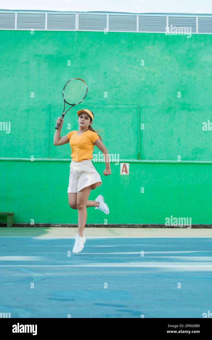 Female tennis player moving in jumping after hitting ball Stock Photo
