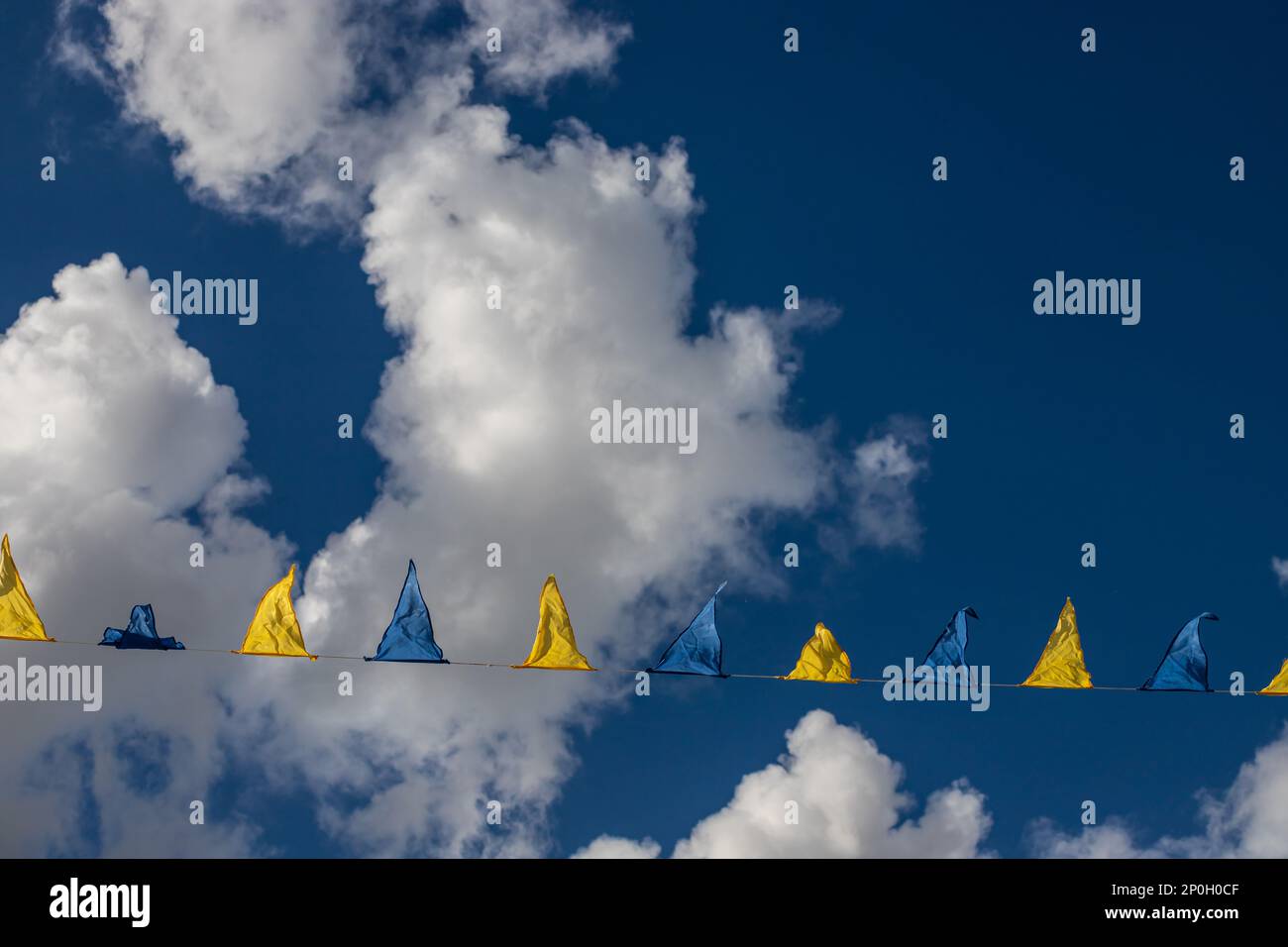 Yellow and blue triangular festival flags on sky background with white ...