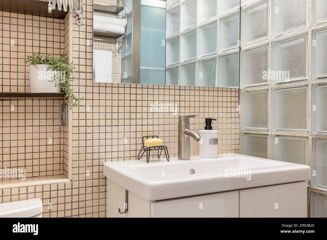 https://c8.alamy.com/comp/2P0HB2K/comfortable-white-sink-with-soap-dish-mirror-on-the-wall-and-shelves-on-beige-mosaic-tile-in-stylish-bathroom-with-glass-tiles-concept-of-stylish-2P0HB2K.jpg