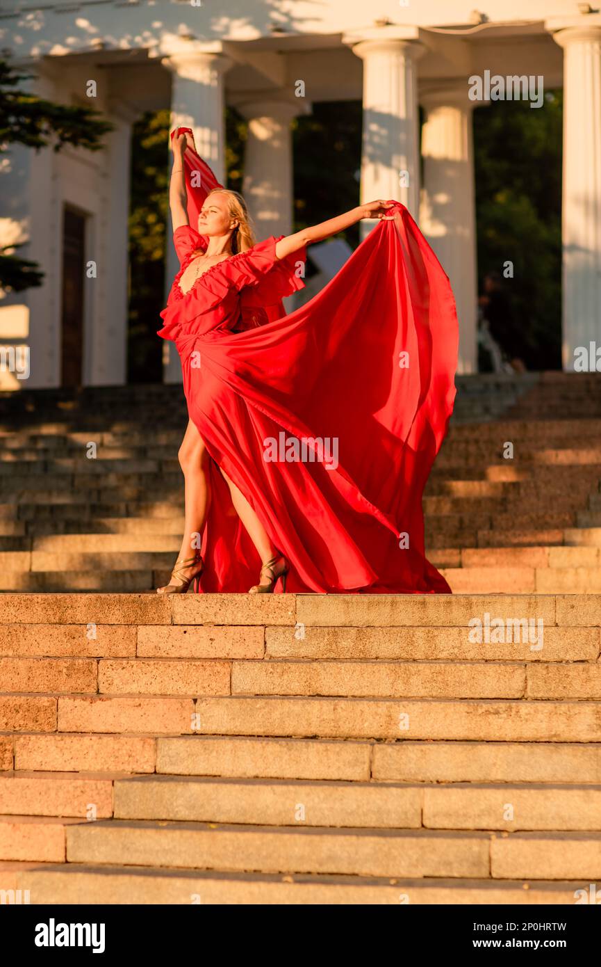 A woman in a long red dress against the backdrop of sunrise, bright golden  light of the sun's rays. The concept of femininity, harmony Stock Photo -  Alamy