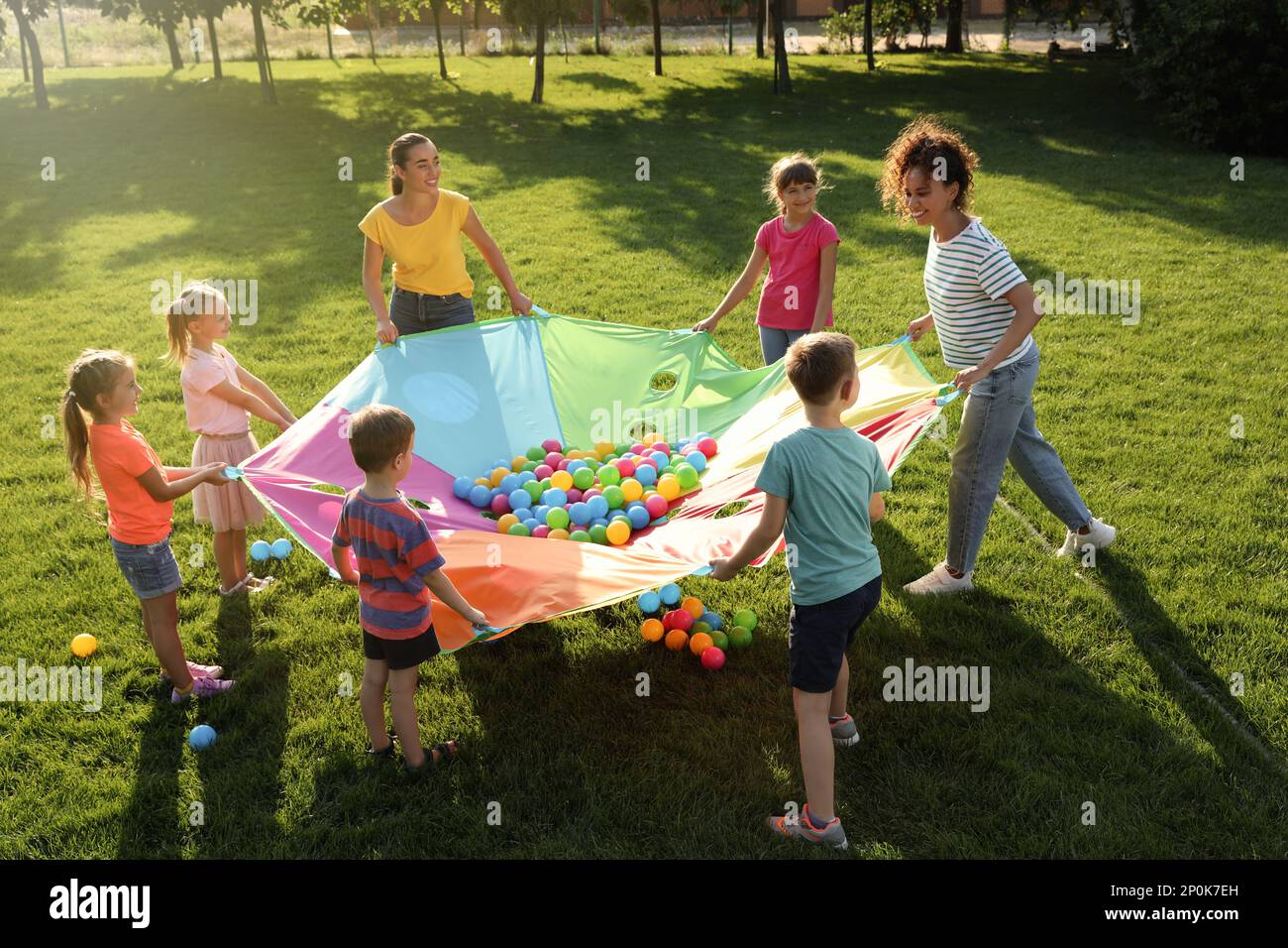 Group of children and teachers playing with rainbow playground