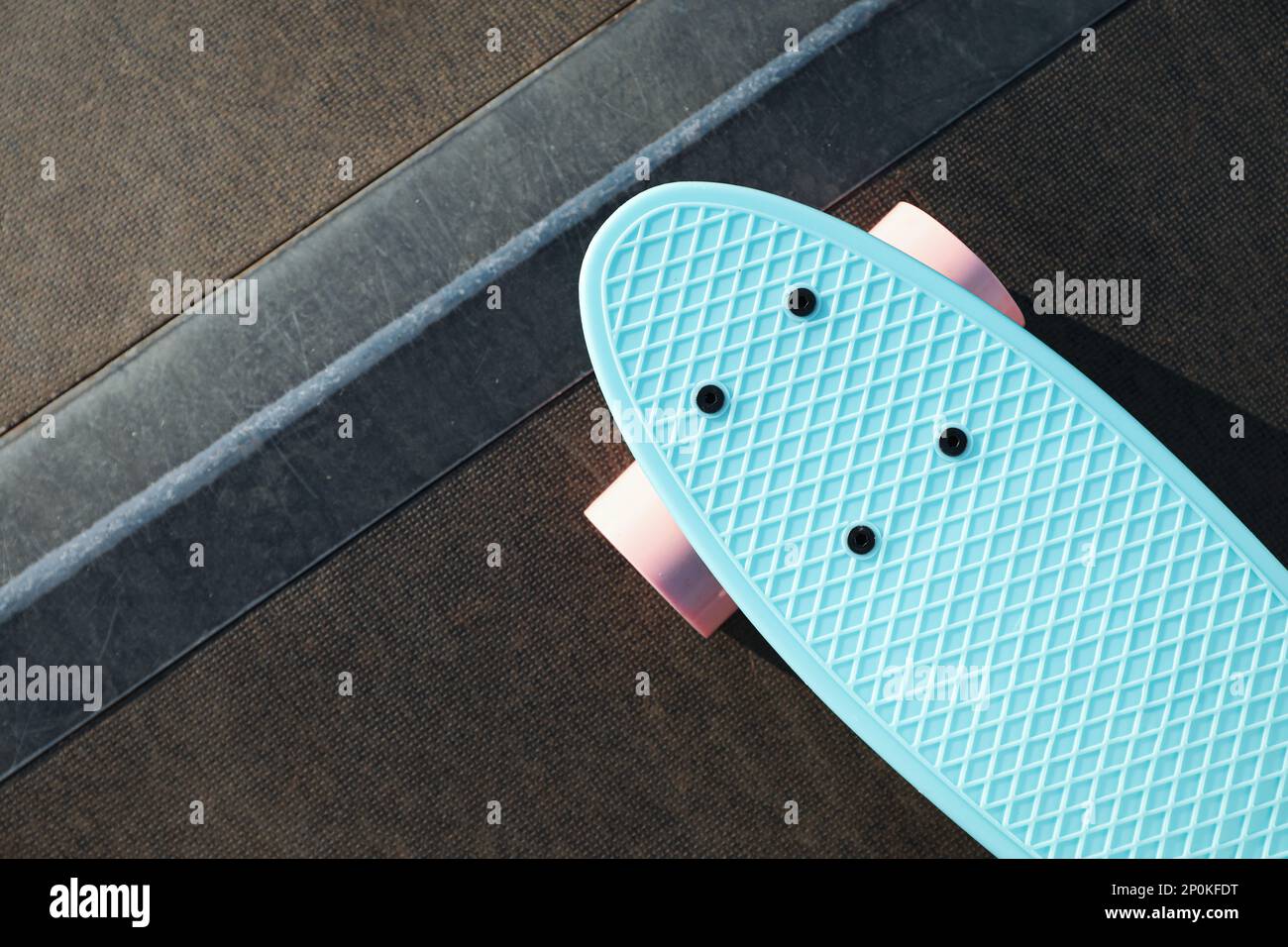 Modern light blue skateboard with pink wheels on ramp outdoors, top ...