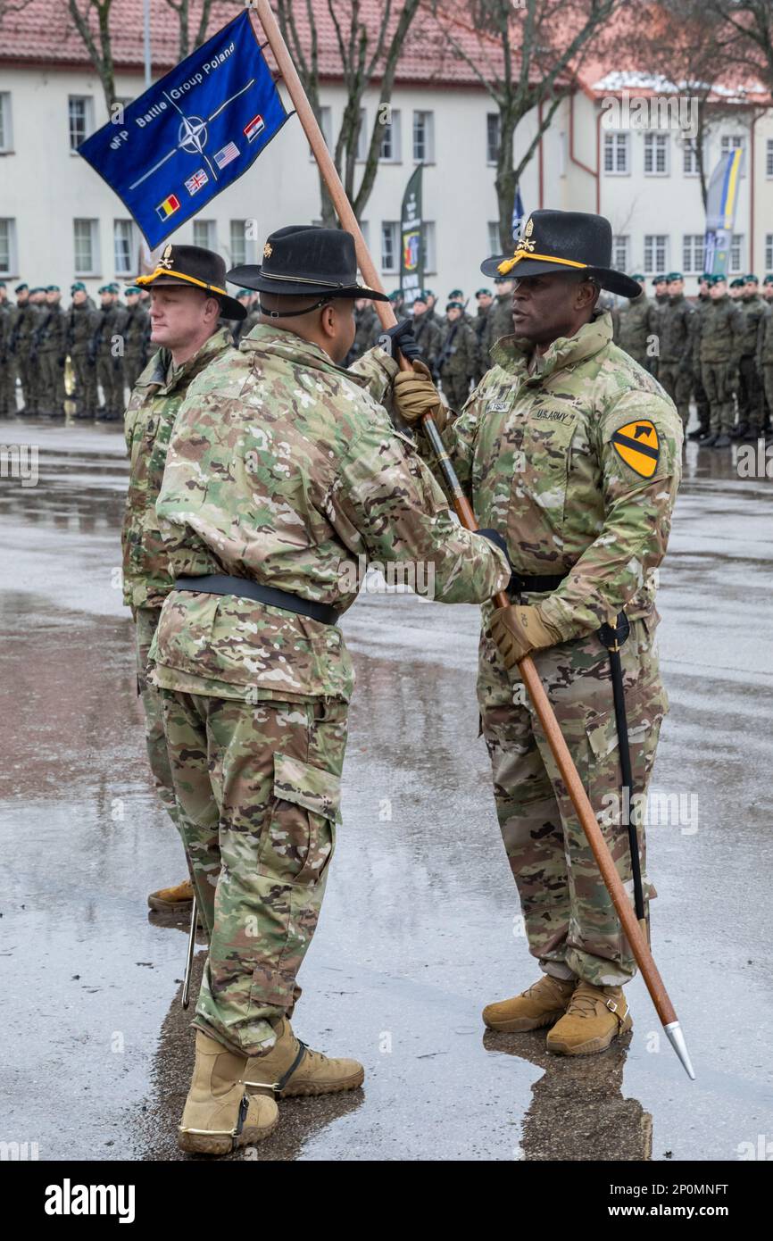 U.S Army Lt. Col. James Ray, left, incoming commander of NATO eFP Battle Group Poland and commander of the 1st Battalion, 9th Cavalry Regiment (1-9 CAV), 2nd Armored Brigade Combat Team (2 ABCT), 1st Cavalry Division (1 CD), operationally controlled by the 4th Infantry Division (4 ID), passes the NATO enhanced Forward Presence Battle Group Poland guidon to Command Sgt. Maj. Sheldon Watson, command sergeant major of eFP Battle Group Poland and the 1-9 CAV, 2 ABCT, 1 CD, during the Hand Over, Take Over ceremony in Bemowo Piskie, Poland, Feb. 2, 2023. The 2 ABCT, 1 CD is among other units assigne Stock Photo