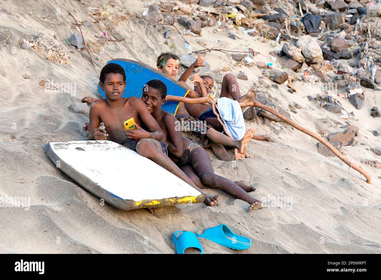 Local boys relaxing on the beach with their boogie boards, on the beach of Sao pedro, sandy beach close to Mindelo on Sao VIcente island, Cabo verde Stock Photo